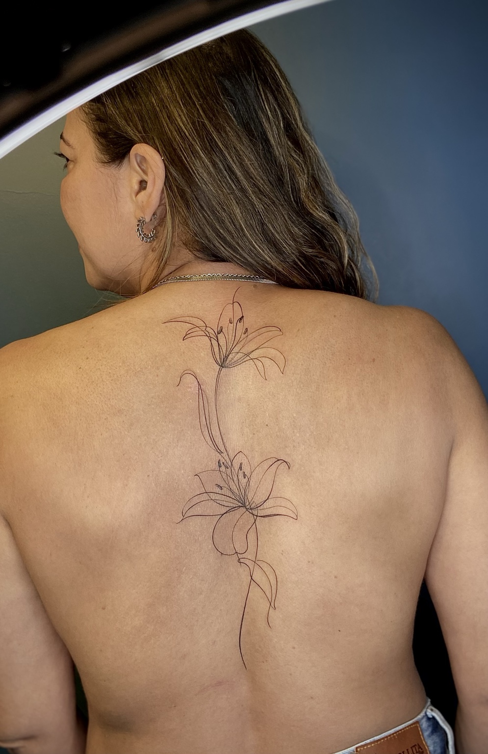 Tatuagem fineline de lírios nas costas