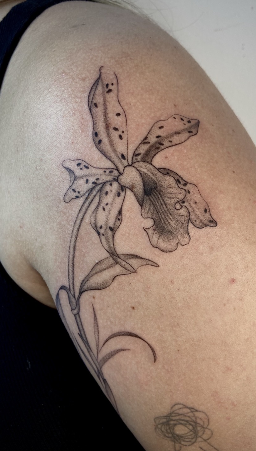 Tatuagem botânica de orquídea acompanhando o braço