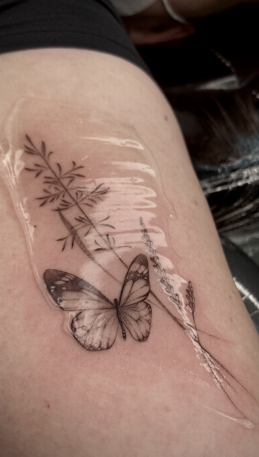 Tatuagem delicada de borboleta entre ramos finos