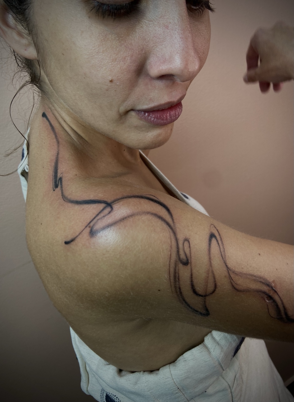 Tatuagem abstrata acompanhando ombro, colo e braço