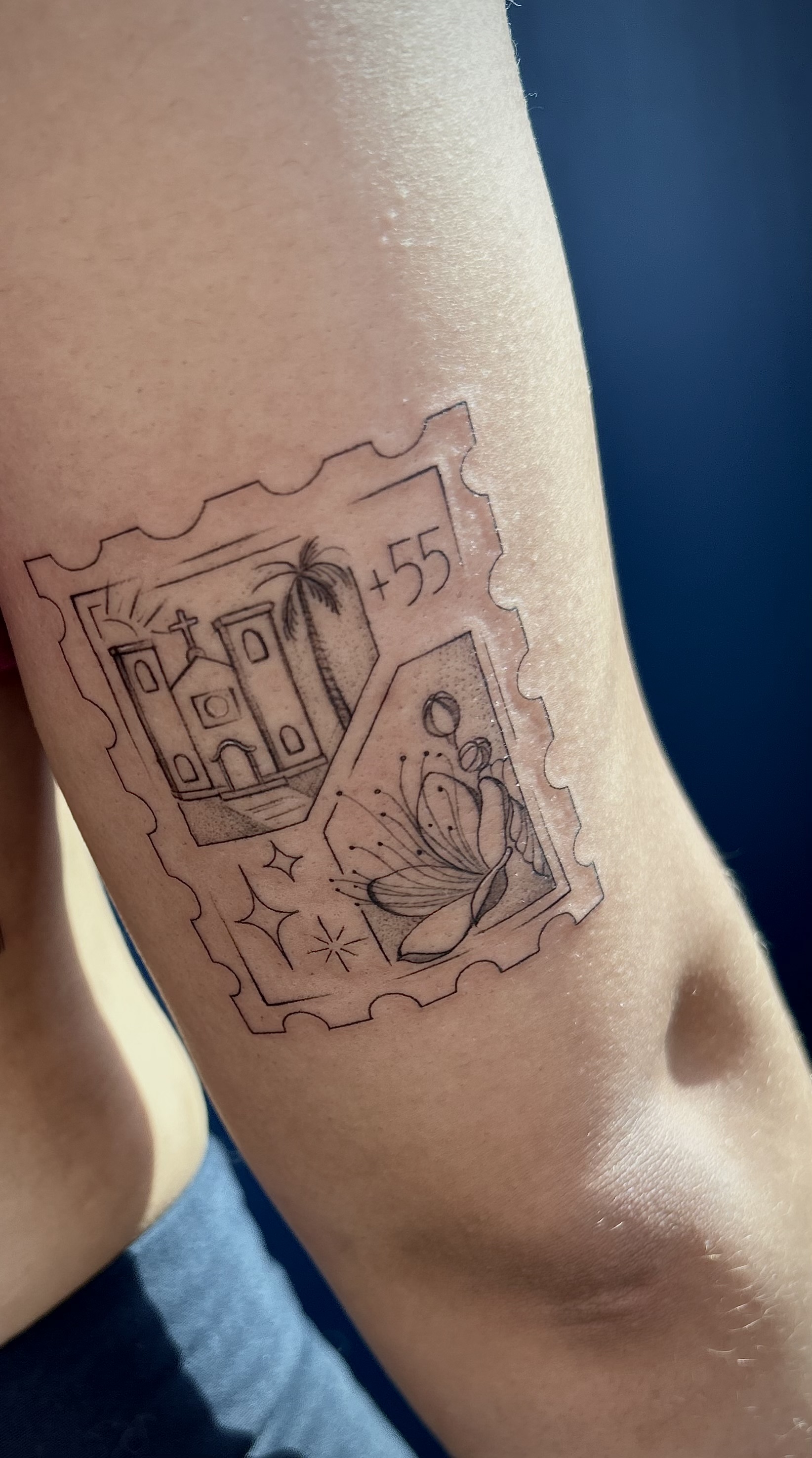 Tatuagem de selo com igreja, borboleta e número 55