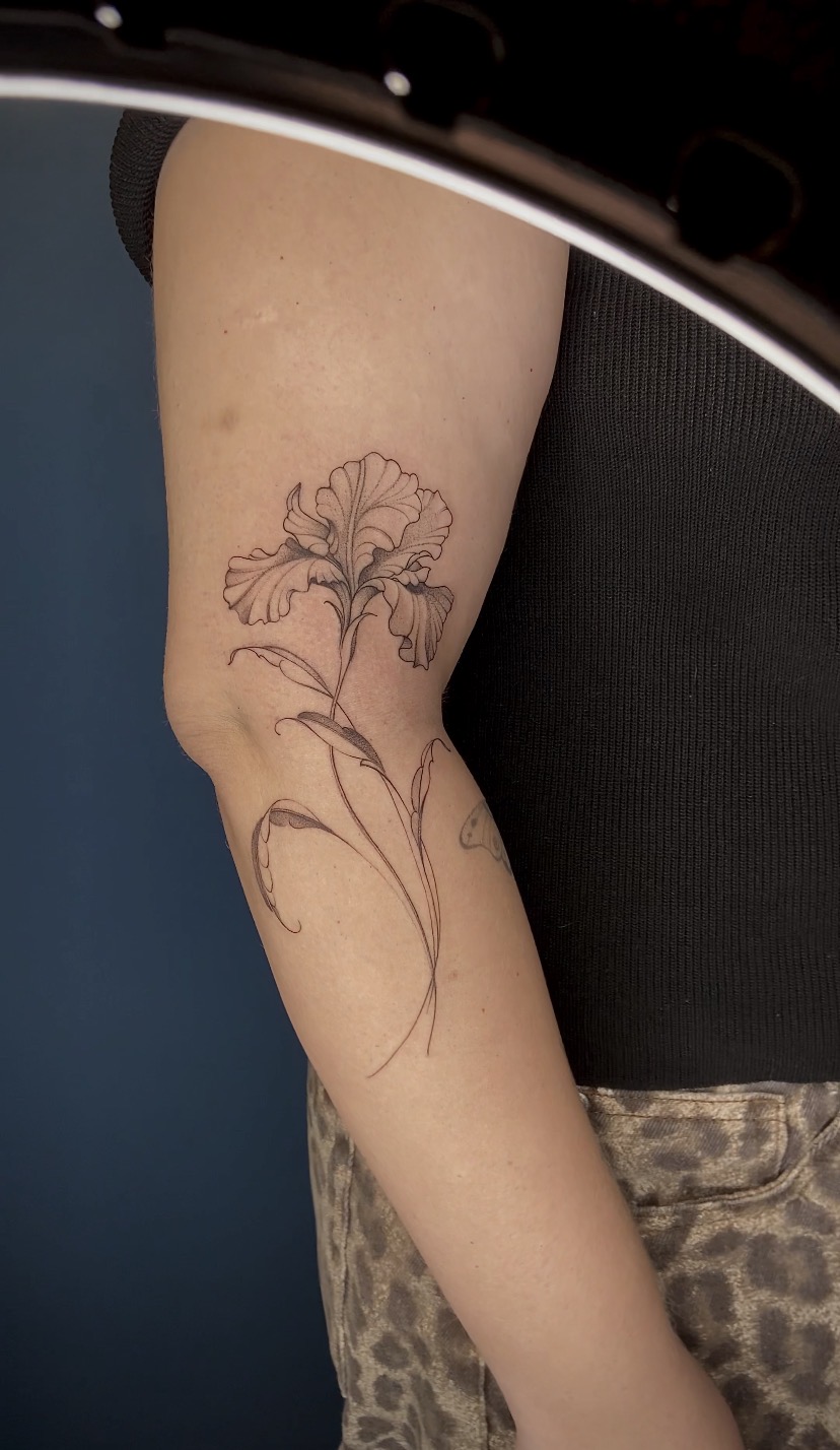 Tatuagem fineline de flor alongada acompanhando o braço